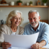 Couple retraité souriant examinant documents financiers